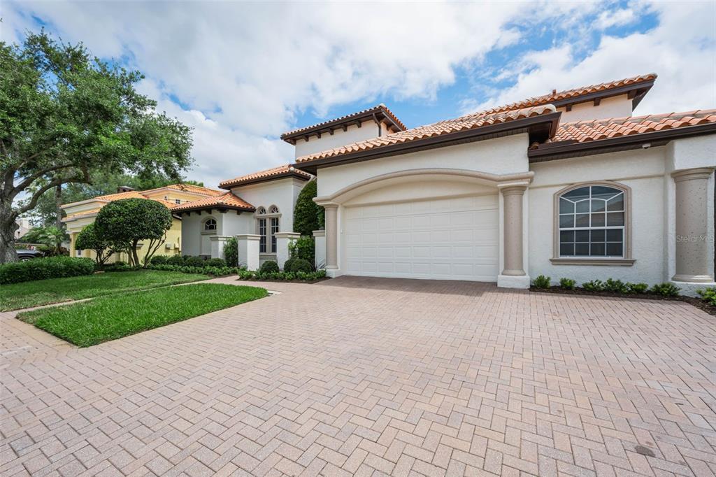 A stucco house with a tiled roof, a large garage, and a brick paver driveway — 1246 TUSCANY DRIVE, TRINITY, FL