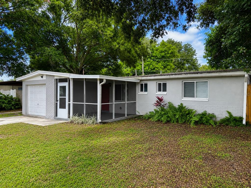 A single-story house with a white garage, screened-in porch, and gray brick exterior — 8836 79TH PLACE, SEMINOLE, FL