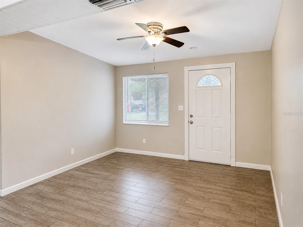 A room with light-colored walls, wood-look tile flooring, a ceiling fan, and an exterior door — 8836 79TH PLACE, SEMINOLE, FL