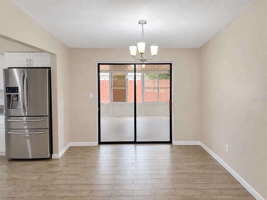 A dining area with wood-look tile flooring, a chandelier, and sliding glass doors to a porch — 8836 79TH PLACE, SEMINOLE, FL