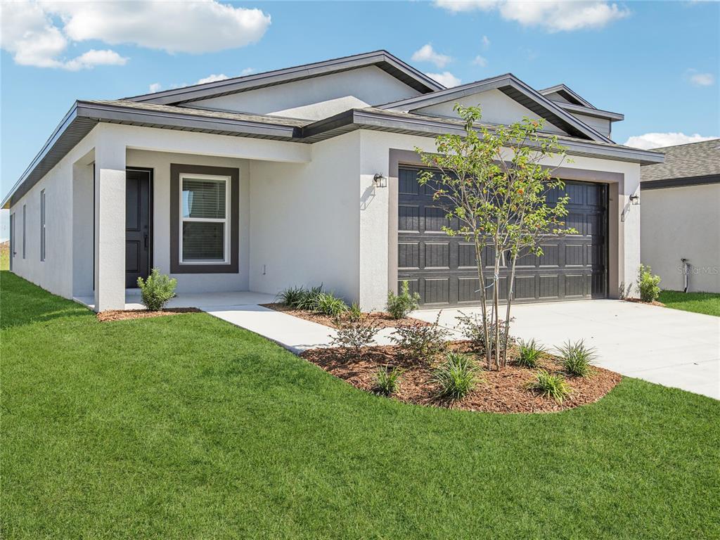 A single-story house with a white stucco exterior, dark garage door, and a front lawn — 5241 CAP ROAD, BROOKSVILLE, FL