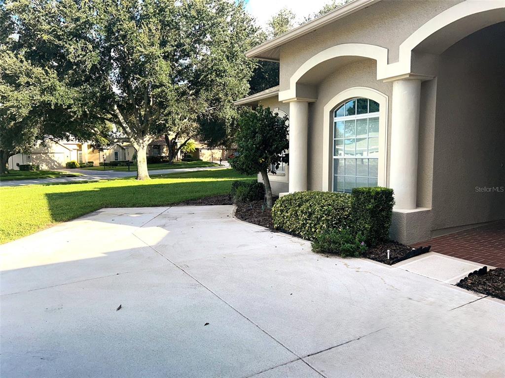 A concrete driveway leads to the entrance of a house with a columned arched entryway — 18754 GRAND CLUB DRIVE, HUDSON, FL