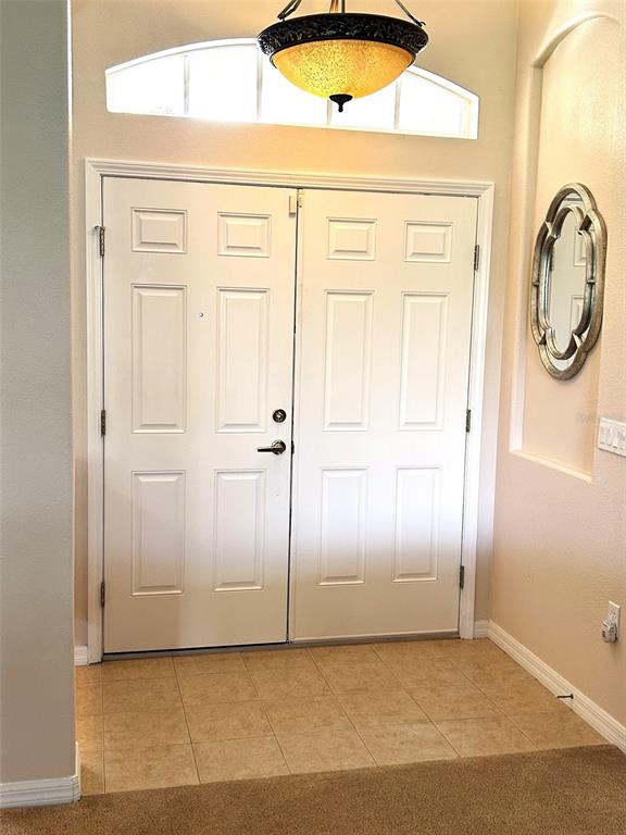 A white double front door with a transom window and a hanging light fixture — 18754 GRAND CLUB DRIVE, HUDSON, FL