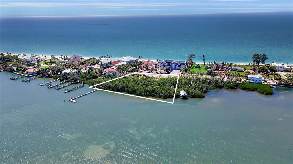 An aerial view shows a vacant, tree-covered waterfront lot outlined in white near the ocean — 2542 CASEY KEY ROAD, NOKOMIS, FL
