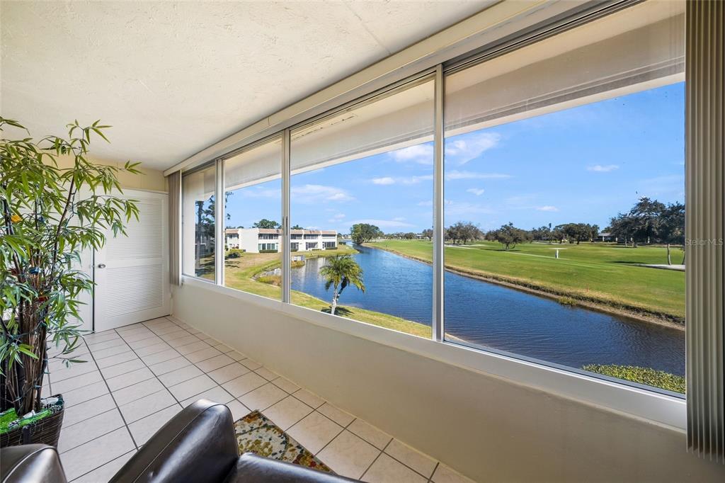 A sunroom with tile flooring overlooks a canal and a golf course through large windows — 7193 W COUNTRY CLUB DRIVE N UNIT 237, SARASOTA, FL