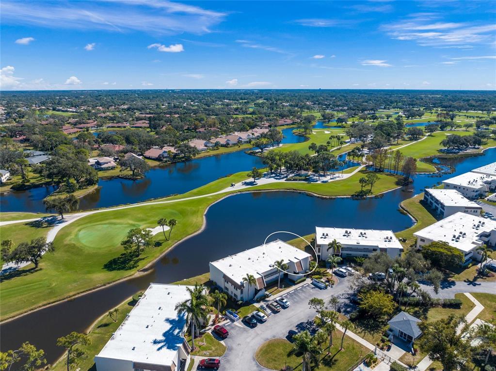 An aerial view shows a multi-story apartment building next to a lake and golf course — 7193 W COUNTRY CLUB DRIVE N UNIT 237, SARASOTA, FL