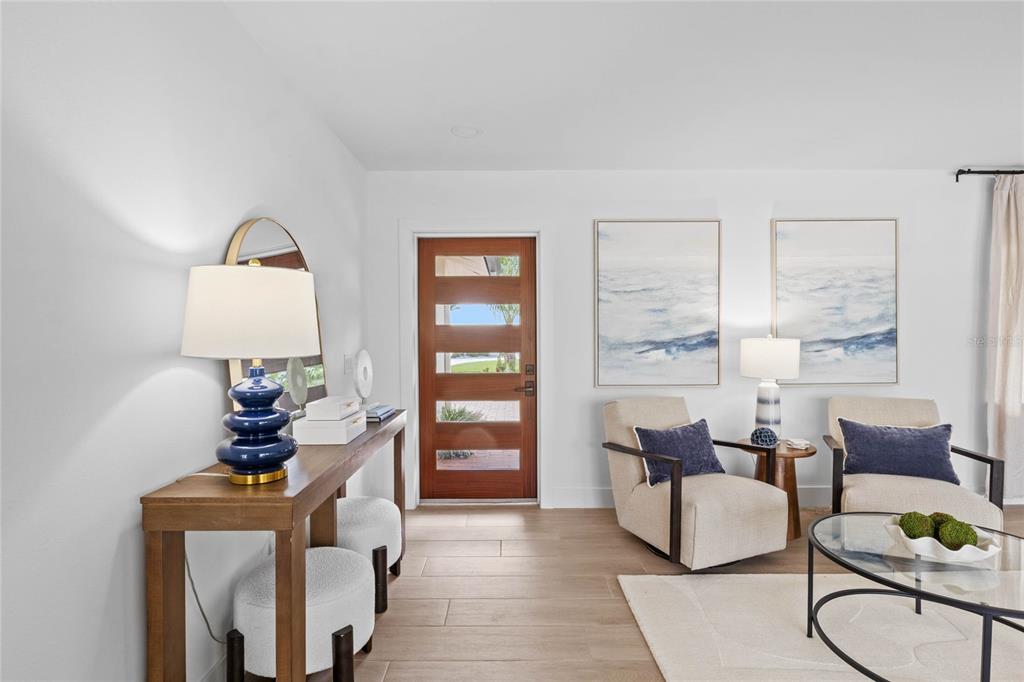 A modern home exterior features a wood front door, white stucco walls, and brick pavers — 624 DUNDEE LANE, HOLMES BEACH, FL