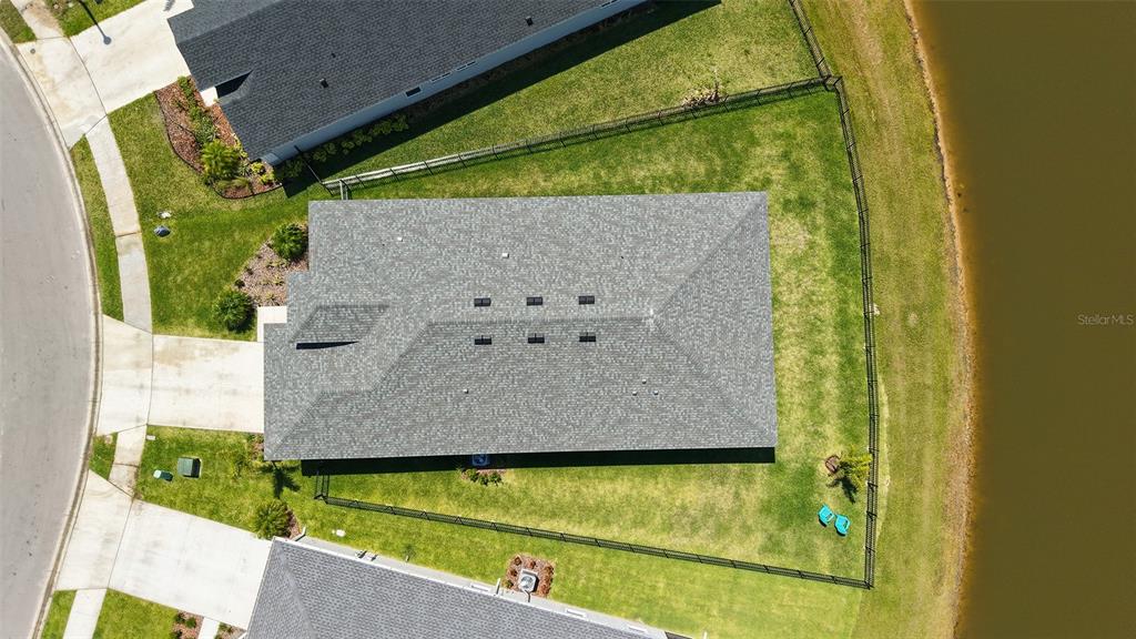 An aerial view shows a house with a gray shingled roof next to a pond — 11869 RICHMOND TRAIL, PARRISH, FL
