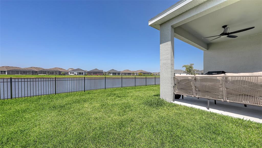 A covered patio with a ceiling fan overlooks a fenced backyard and a lake — 11869 RICHMOND TRAIL, PARRISH, FL