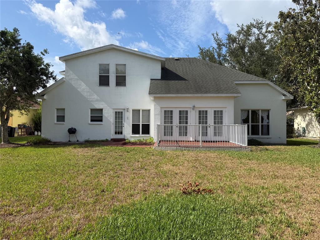 The rear exterior of a two-story white house features a patio with a metal railing — 9250 NW 13TH AVENUE CIRCLE, BRADENTON, FL
