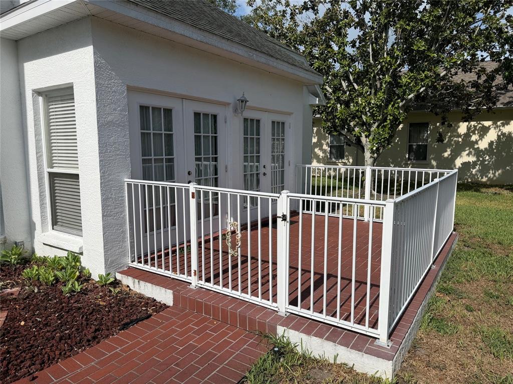 A white house features a brick patio enclosed by a white metal fence and gate — 9250 NW 13TH AVENUE CIRCLE, BRADENTON, FL