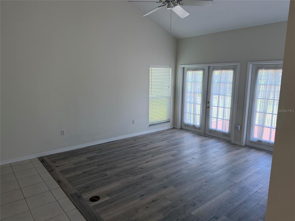 A living room with vaulted ceilings, wood-look flooring, and glass doors leading to the outdoors — 9250 NW 13TH AVENUE CIRCLE, BRADENTON, FL