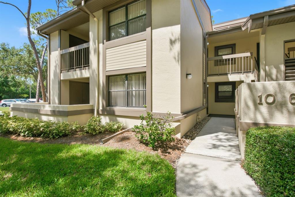 A two-story apartment building exterior with a concrete walkway leading to the entrance — 10 WOODLAKE PLACE, OLDSMAR, FL