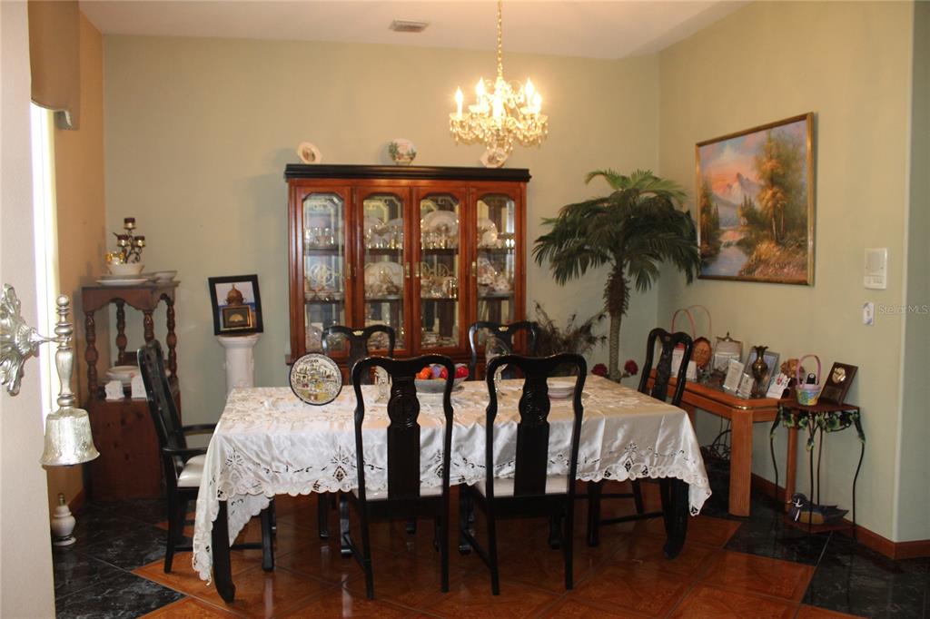 A formal dining room features a wooden china cabinet, a chandelier, and a table setting — 4900 S ORANGE BLOSSOM TRAIL, KISSIMMEE, FL