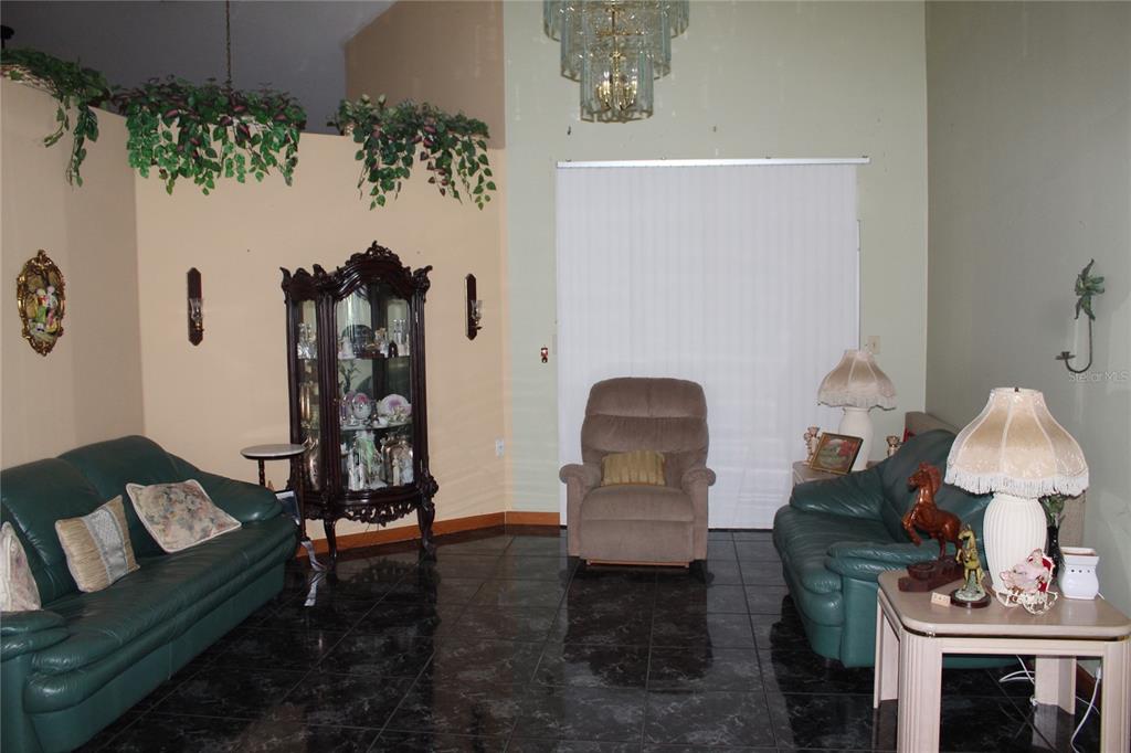 A living room features dark tile floors, two green leather sofas, and a central recliner — 4900 S ORANGE BLOSSOM TRAIL, KISSIMMEE, FL