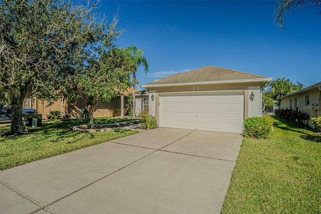 A single-story house with a white garage door and a concrete driveway under a clear sky — 9608 ROLLING CIRCLE, SAN ANTONIO, FL