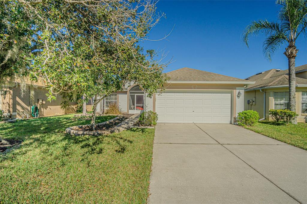 A single-story house with a white garage door, a concrete driveway, and a front lawn — 9608 ROLLING CIRCLE, SAN ANTONIO, FL