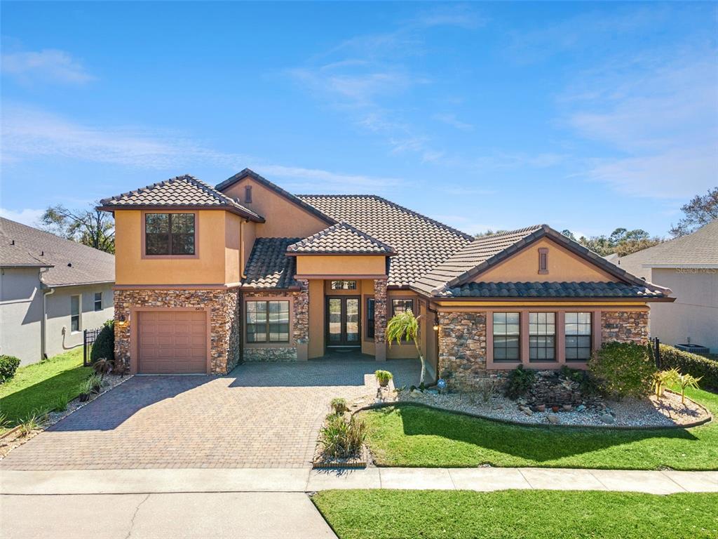 A two-story house with a stone facade, tile roof, and a paved driveway — 6473 EVERINGHAM LANE, SANFORD, FL
