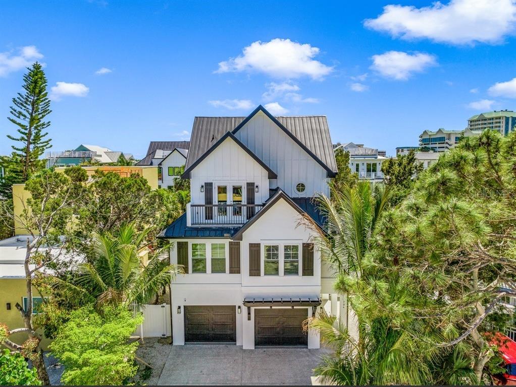 A three-story white house with a metal roof, two garage doors, and a balcony — 204 COOLIDGE DRIVE, SARASOTA, FL