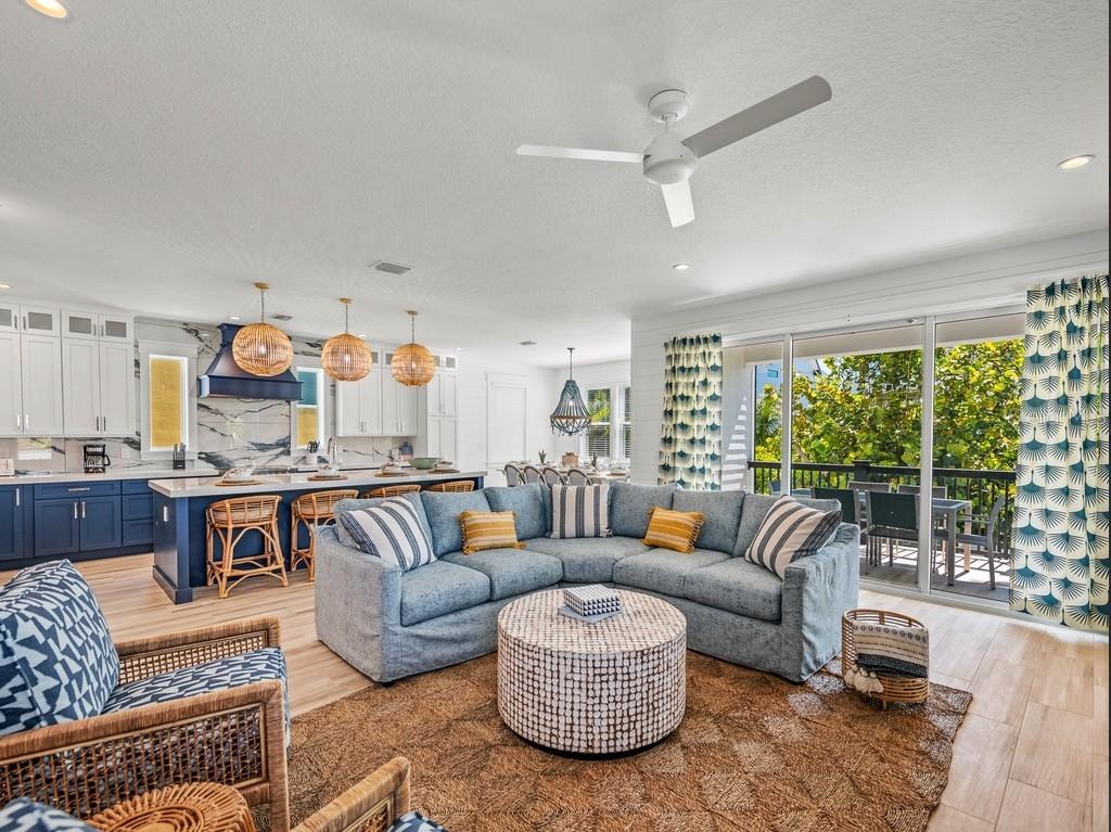 An open-concept living room and kitchen with blue cabinetry, a sectional sofa, and balcony access — 204 COOLIDGE DRIVE, SARASOTA, FL