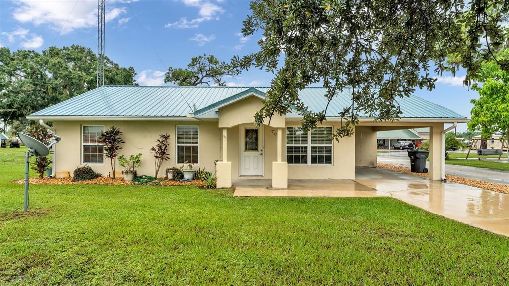 A single-story house with a light-colored exterior, metal roof, and an attached carport — 701 KEEN ROAD, FROSTPROOF, FL