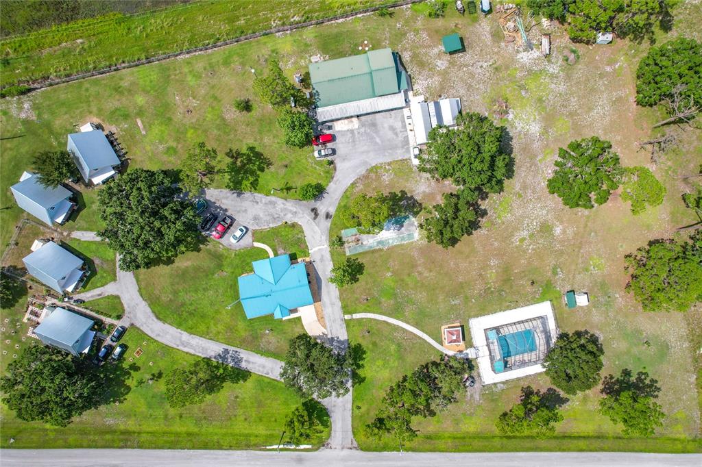 An aerial view shows a property with several buildings, a pool, and paved driveways — 701 KEEN ROAD, FROSTPROOF, FL