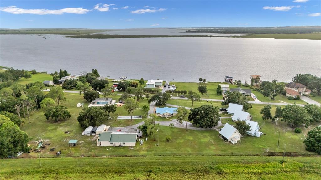 An aerial view shows several houses situated on a grassy lot along a large lake — 701 KEEN ROAD, FROSTPROOF, FL