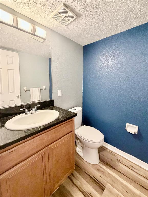 A bathroom features a wood vanity with a dark countertop, a toilet, and blue walls — 724 HAVEN PLACE UNIT 724, TARPON SPRINGS, FL