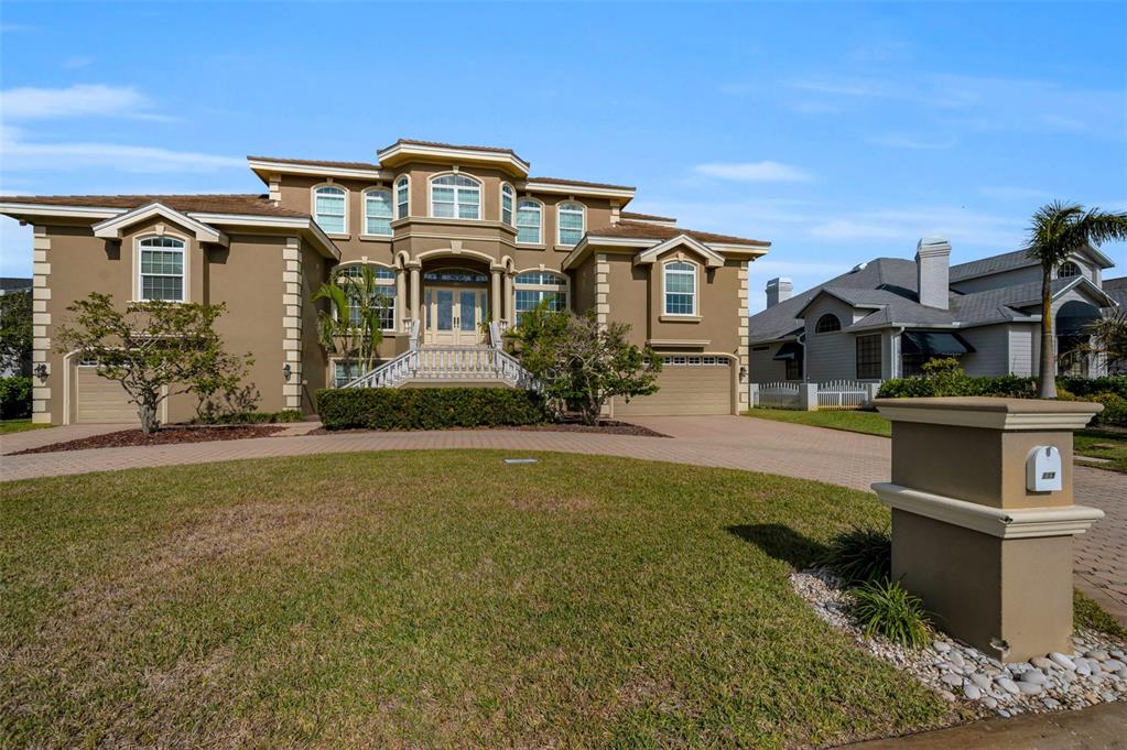 A large, two-story tan stucco house with a paved driveway and a front-facing mailbox — 119 8TH STREET E, TIERRA VERDE, FL
