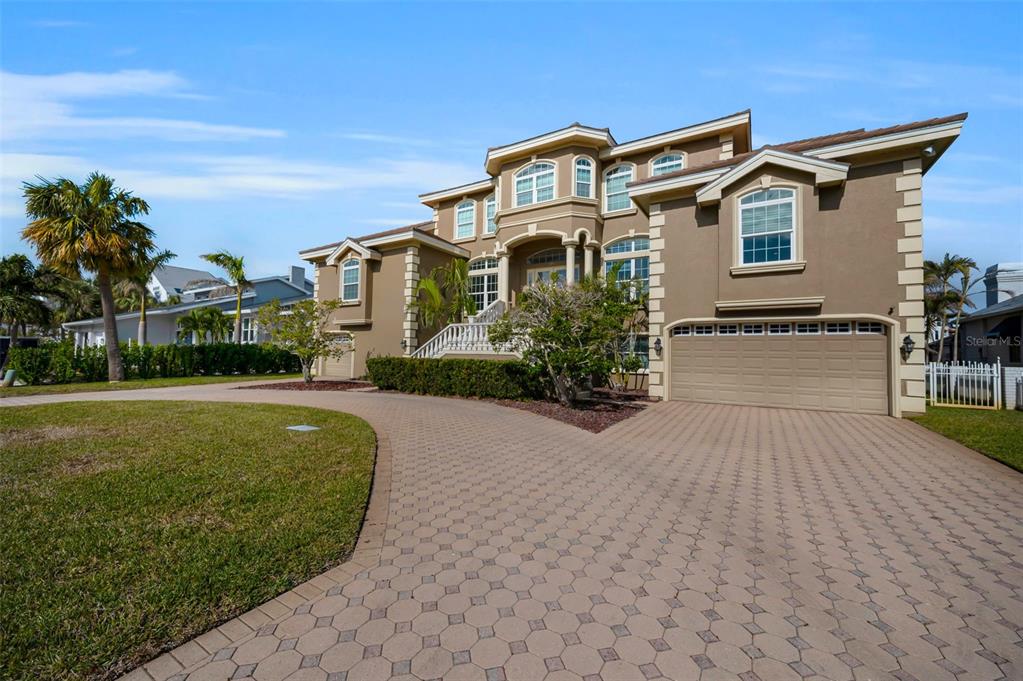 A large, multi-story tan house with a paved driveway and a two-car garage — 119 8TH STREET E, TIERRA VERDE, FL