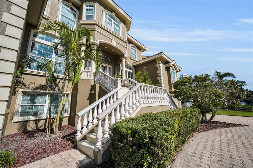 A multi-story house exterior features a white balustrade staircase leading to an elevated front entrance — 119 8TH STREET E, TIERRA VERDE, FL