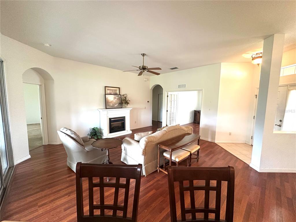 A living room features wood flooring, a fireplace, a ceiling fan, and arched doorways — 12173 SE 178TH STREET, SUMMERFIELD, FL