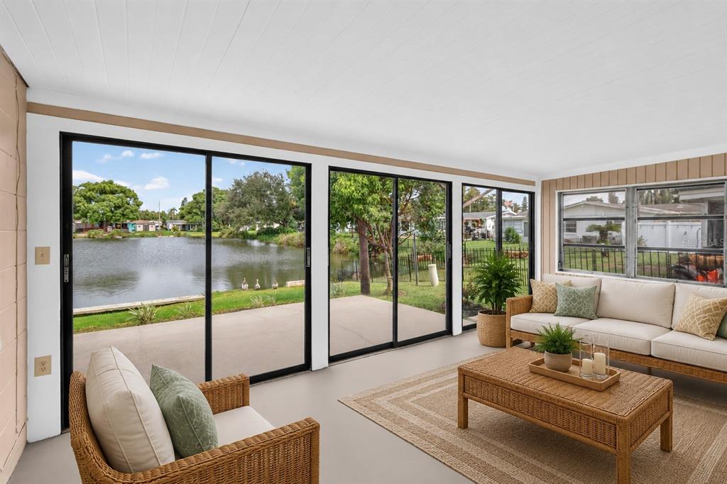 A grassy backyard overlooks a calm pond with a small dock and two ducks — 2044 PAMELA DRIVE, HOLIDAY, FL