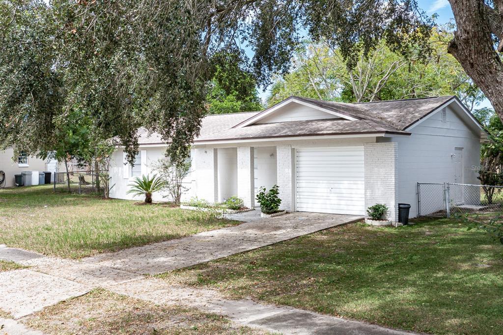 A white single-story house with a garage, a concrete driveway, and a large front yard — 610 E HELM WAY, CASSELBERRY, FL