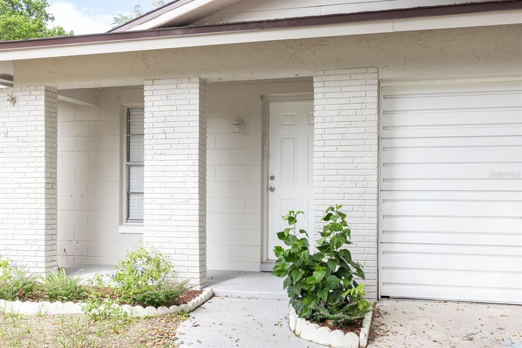 The exterior of a house features a white brick facade, a front door, and a garage — 610 E HELM WAY, CASSELBERRY, FL