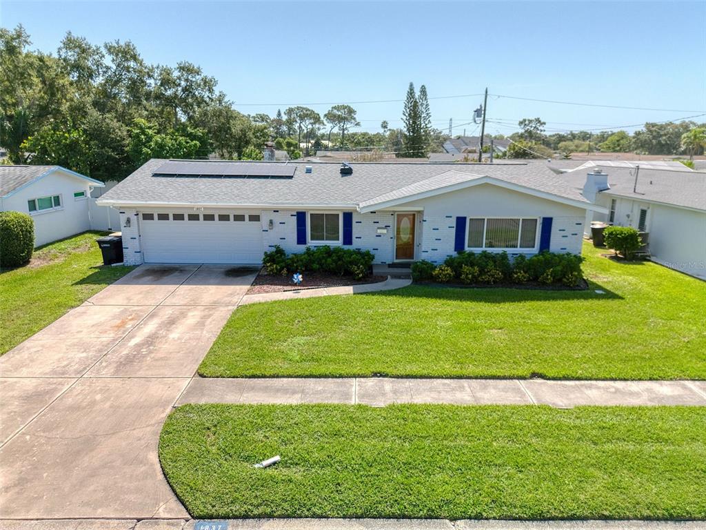 A single-story house with a white brick exterior, a two-car garage, and rooftop solar panels — 1837 PRINCETON, CLEARWATER, FL