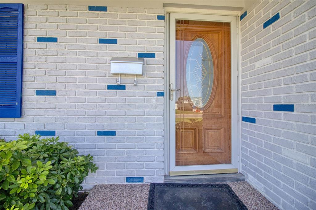 A front entryway features a white brick wall with blue accents, a mailbox, and a door — 1837 PRINCETON, CLEARWATER, FL