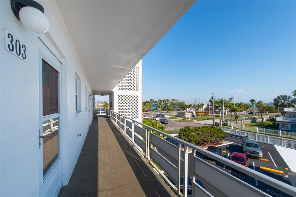 An exterior balcony with a metal railing overlooks a parking lot and a coastal street — 3128 59TH STREET S UNIT 303, GULFPORT, FL