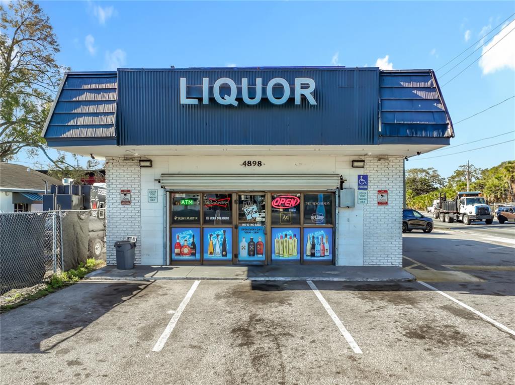 A single-story liquor store building with a blue metal awning and white brick facade — 4898 EDGEWATER DRIVE, ORLANDO, FL