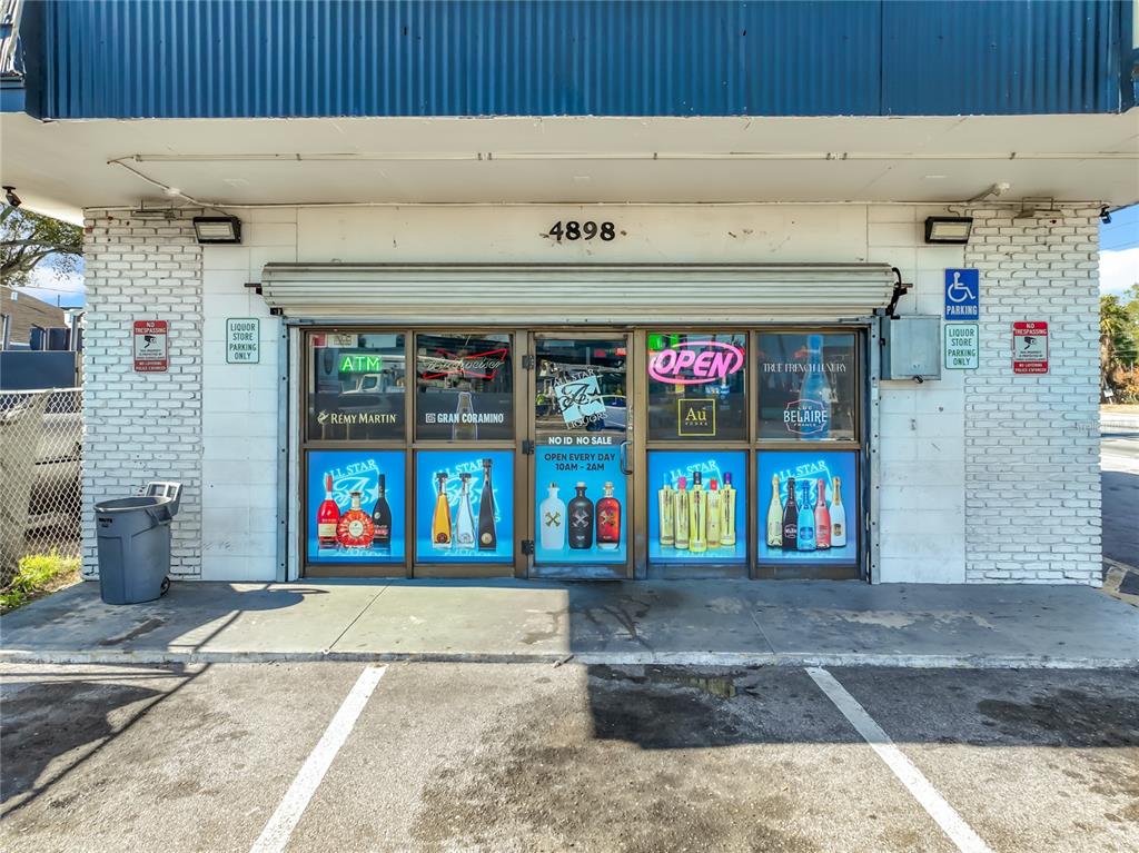 The exterior of a liquor store features a brick facade, glass storefront windows, and a roll-down security gate — 4898 EDGEWATER DRIVE, ORLANDO, FL