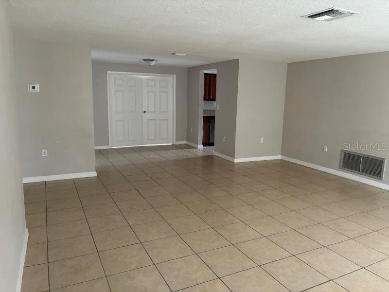 A spacious room with light-colored tile flooring, gray walls, and a set of double doors — 9425 LIDO LANE, PORT RICHEY, FL