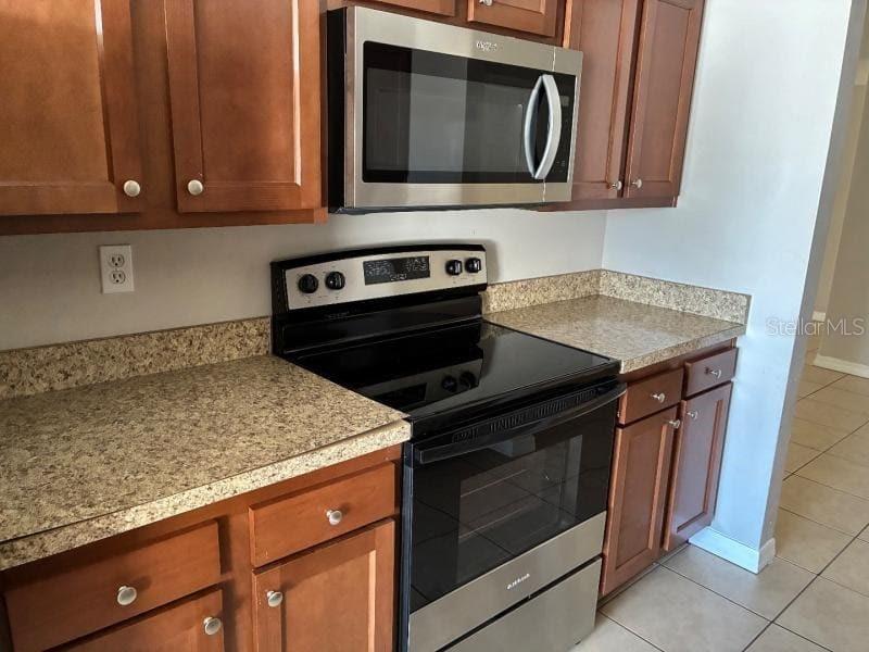 A kitchen features wooden cabinets, stainless steel appliances, and speckled laminate countertops — 9425 LIDO LANE, PORT RICHEY, FL