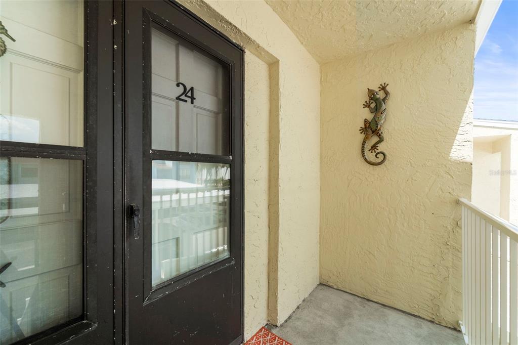 A dark brown storm door with the number 24 leads to a small, stucco-walled balcony — 1 WINDRUSH BOULEVARD UNIT 24, INDIAN ROCKS BEACH, FL