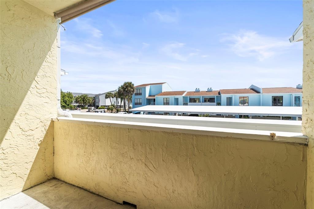 An outdoor balcony with a stucco wall and a view of neighboring apartment buildings — 1 WINDRUSH BOULEVARD UNIT 24, INDIAN ROCKS BEACH, FL