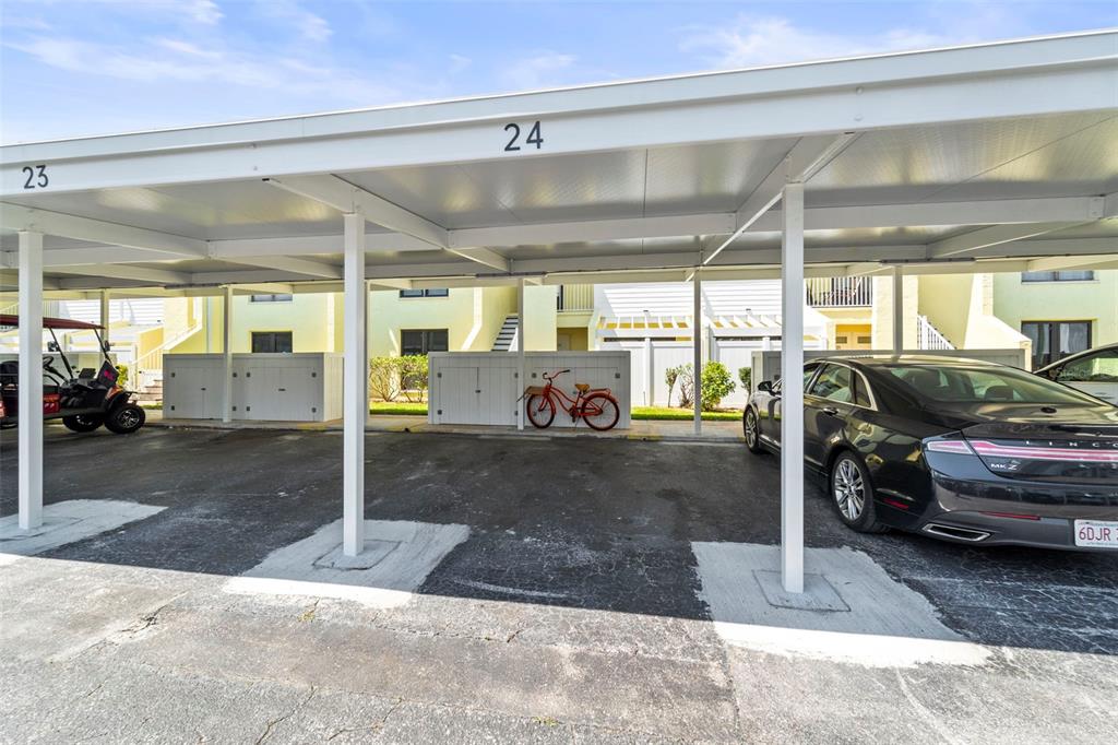 A covered parking area features numbered spaces, a golf cart, a bicycle, and a car — 1 WINDRUSH BOULEVARD UNIT 24, INDIAN ROCKS BEACH, FL
