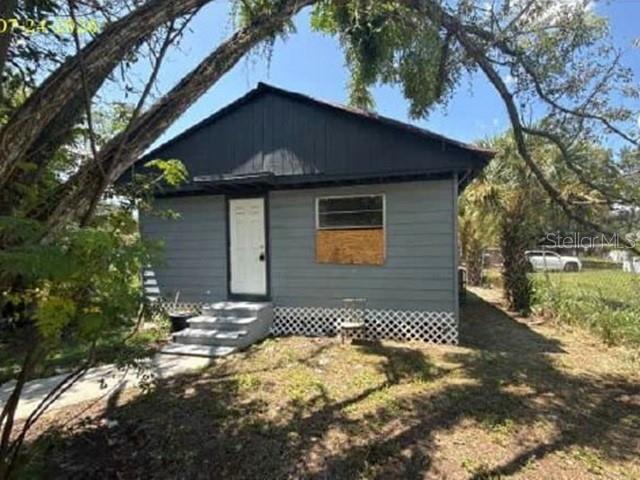 A small, gray, single-story house with a white door and a boarded-up window — 2623 E 29TH AVENUE, TAMPA, FL