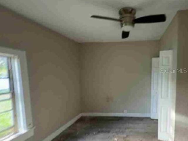 An empty bedroom features beige walls, a ceiling fan, a window, and white closet doors — 2623 E 29TH AVENUE, TAMPA, FL