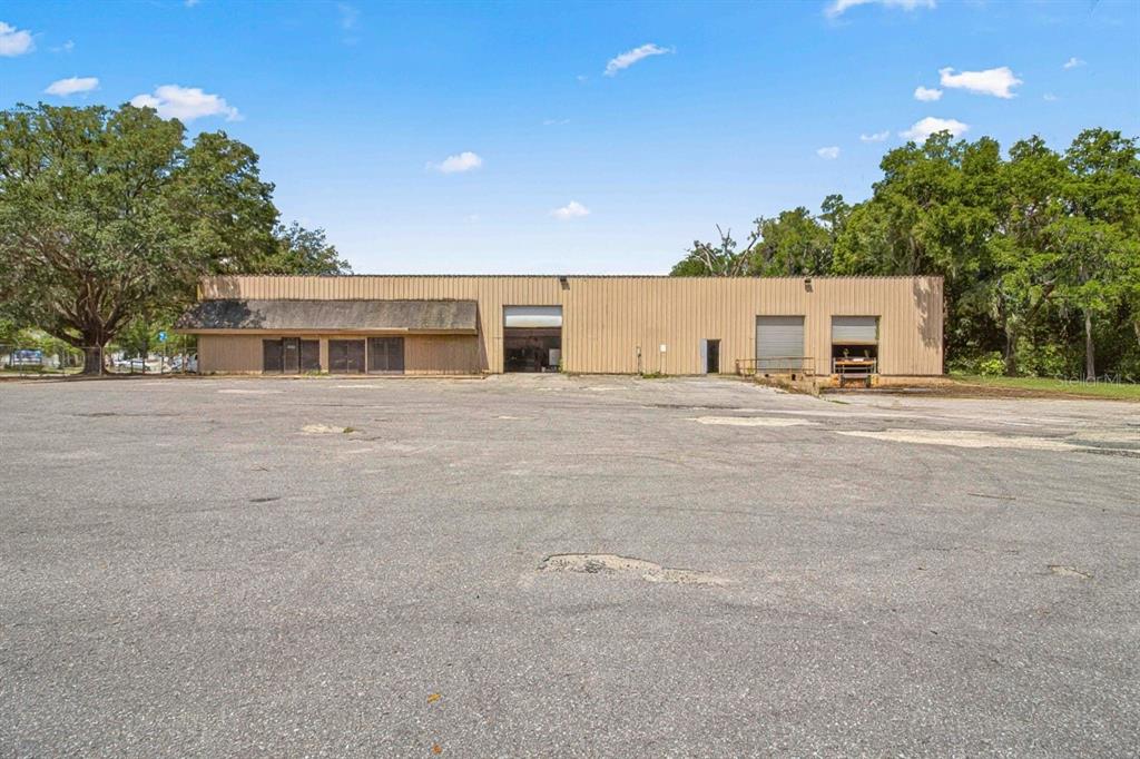 A large, single-story metal industrial warehouse building sits behind a wide, paved parking lot — 1031 NE 16TH STREET, OCALA, FL