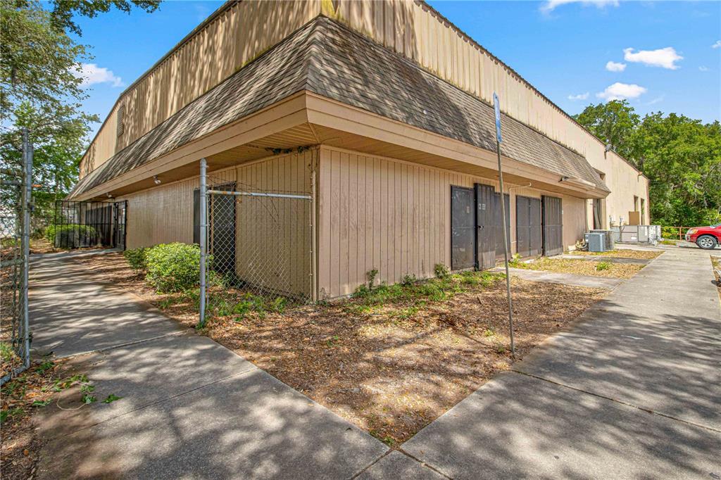 The exterior of a commercial building features tan siding, a mansard roof, and chain-link fencing — 1031 NE 16TH STREET, OCALA, FL