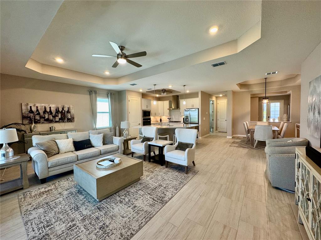 An open-concept living room features a tray ceiling, tile flooring, and a kitchen island — 19140 CHERRYSTONE WAY, LAKEWOOD RANCH, FL
